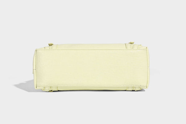 Pale yellow leather-look barrel bag with silver grommet-studded shoulder straps, top zip closure, and pink tulip floral