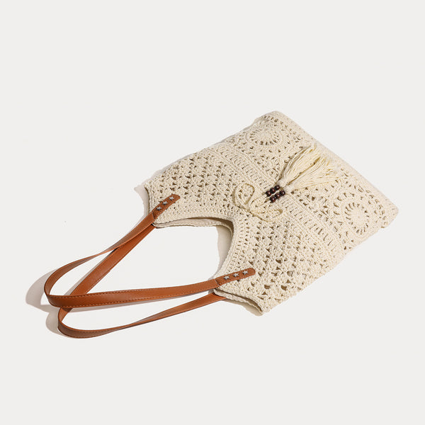 Cream openwork crochet tote bag with tan leather-look double shoulder straps and tassel drawstring tie, detail view 3