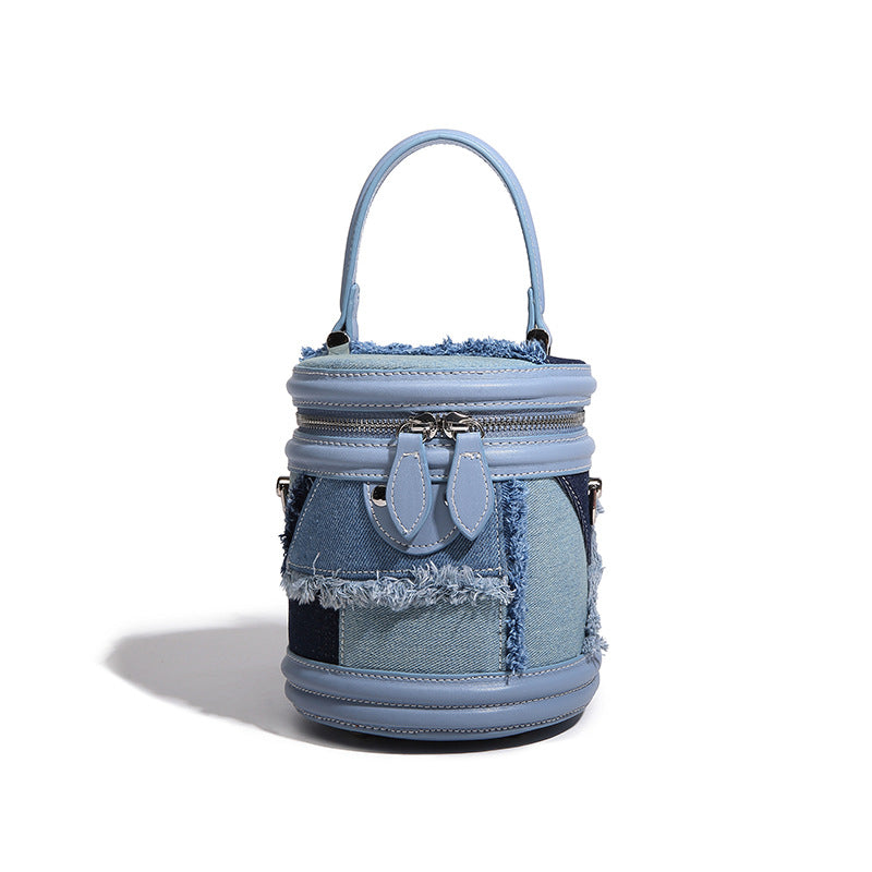 Mini cylindrical barrel bucket bag in denim patchwork with frayed edges, smooth leather-look trim, zip-around top closure
