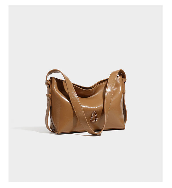 Lässige Hobo-Schultertasche mit offenem oberen Abschluss in glänzender karamellfarbener Lederoptik mit goldfarbenen Logo-Beschlägen und langem, verstellbarem