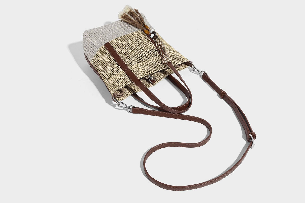 Two-tone open-weave tote bag in beige and cream with brown leather-look handles, tassel bead charm, and detachable