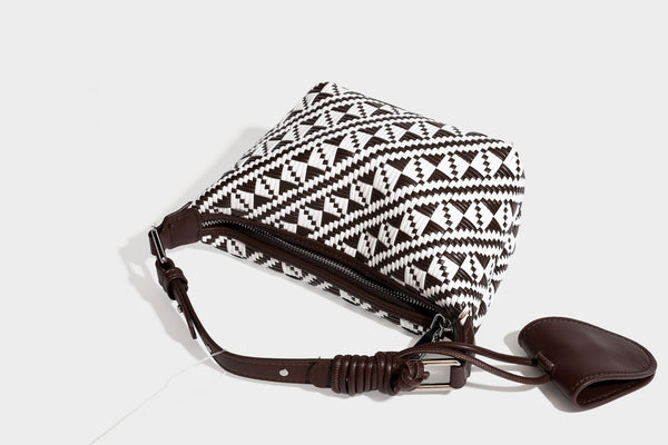 Kleine schwarz-weiße Schultertasche mit gewebtem geometrischem Muster, glatter dunkelbrauner Besatz aus Lederoptik, geknotetem verstellbarem Riemen und seitlichem