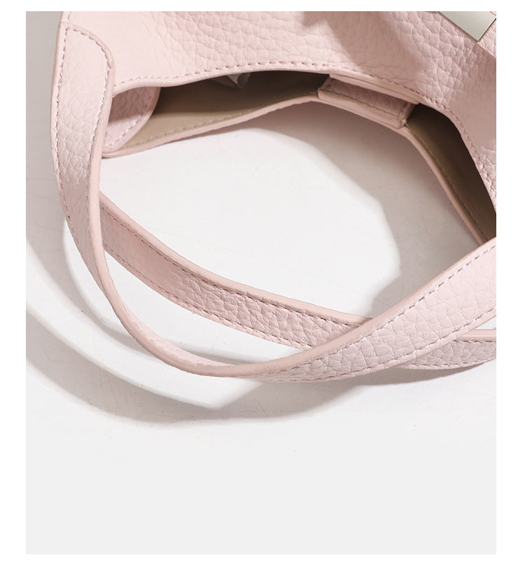 Compact pebbled leather-look shoulder bag with crossed silver-toned metal front closure, short top handle, and long, detail