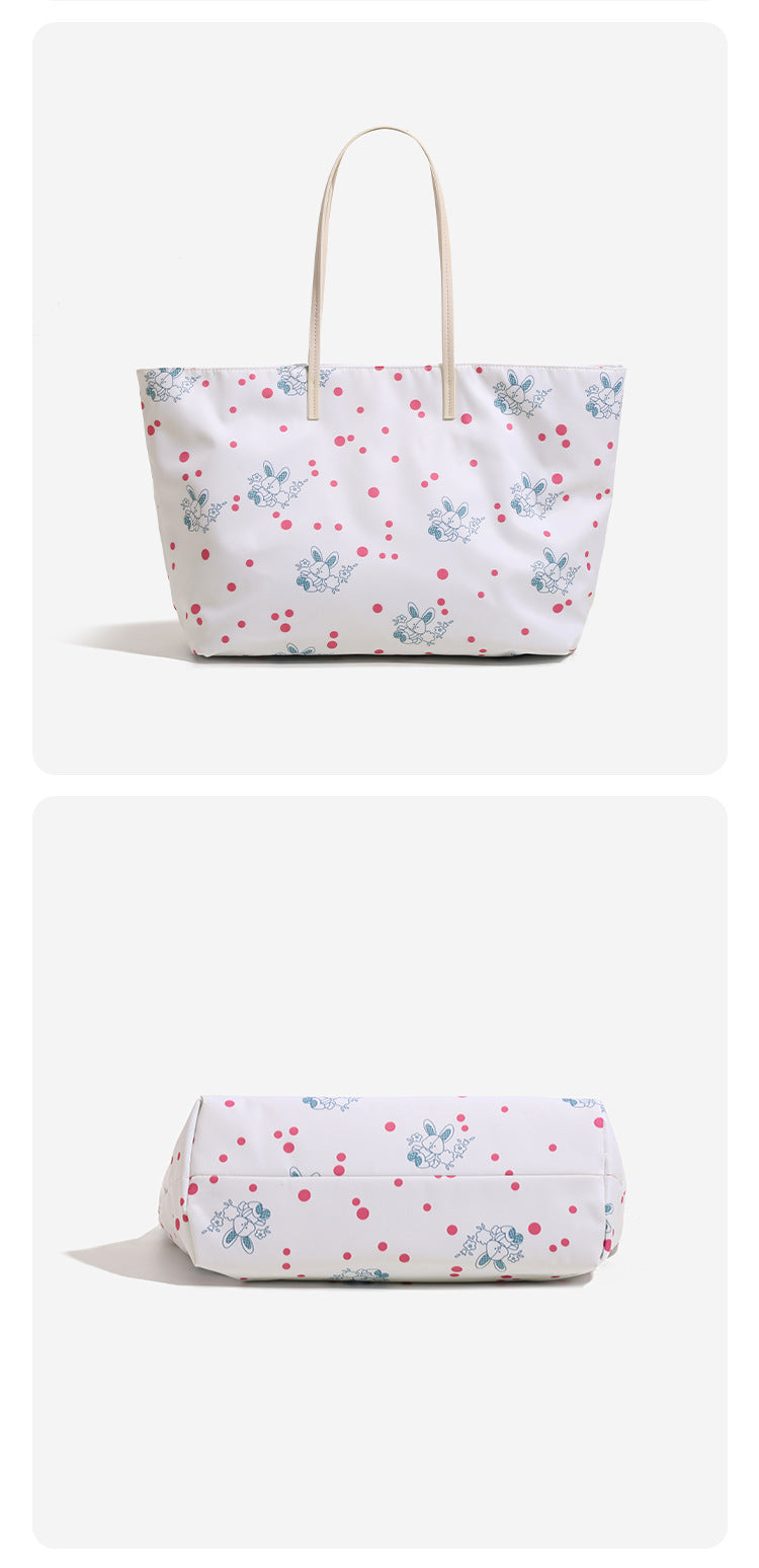 Large reversible floral print tote bag with slim shoulder straps, star charm hardware, and matching zip pouch, detail view 10