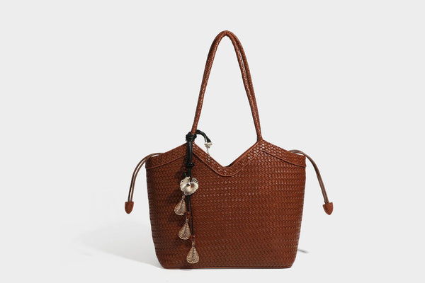 Olivgrüne Tote-Bag in Korbgeflecht-Optik mit dunkelbraunen geflochtenen Schulterriemen, seitlichen Kordelzügen und Perlenanhänger in Goldoptik