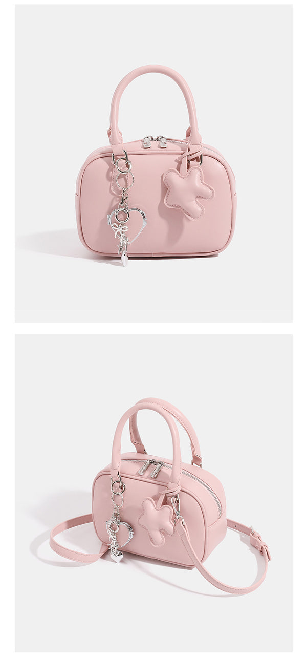 Small structured rounded-rectangle mini handbag with glossy leather-look finish, top zip closure, silver-tone hardware, and