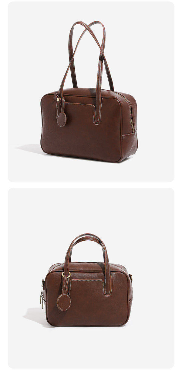Structured boxy bowling-style tote bag in deep brown leather-look finish with dual top handles, front slip pocket, round