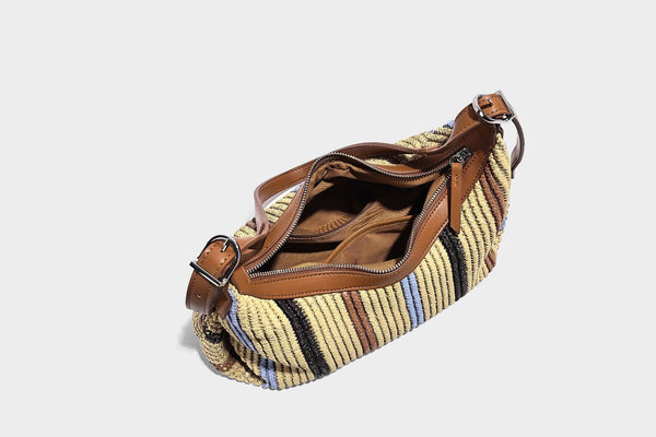 Slouchy woven straw hobo shoulder bag with beige, black, brown, and blue vertical stripes and brown leather-look trim, detail