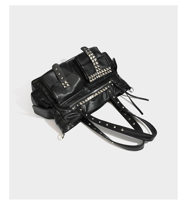 Black leather-look tote bag with silver pyramid studs on handles and front panel, multiple flap and zip exterior pockets