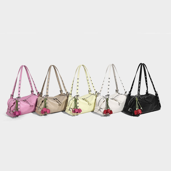 Pale yellow leather-look barrel bag with silver grommet-studded shoulder straps, top zip closure, and pink tulip floral
