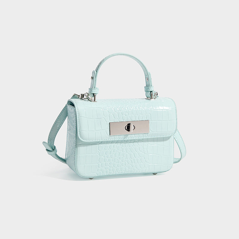 Small structured rectangular satchel with glossy crocodile-embossed finish, arched top handle, front flap, and silver-tone