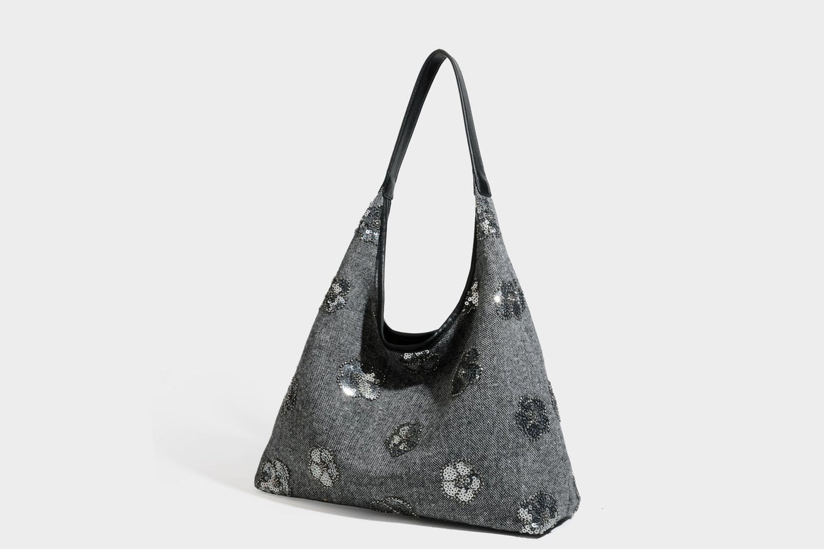Lässig fallende, trapezförmige Schulter-Tote in Anthrazitgrau mit floralen Paillettenmotiven in Silber, Riemen in Lederoptik und herabhängendem Perlenbesatz