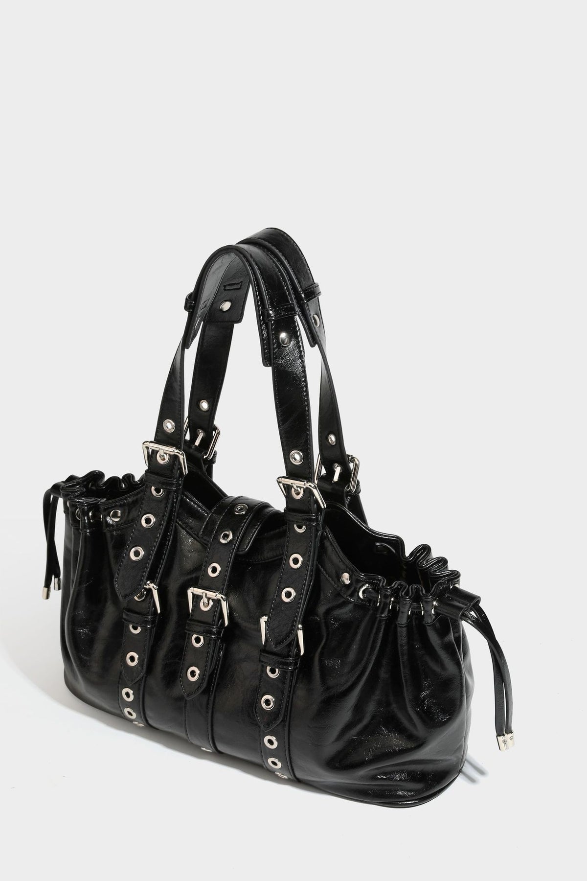 Large black glossy leather-look tote bag with silver buckle straps, eyelet grommet panels, drawstring side gathers, and