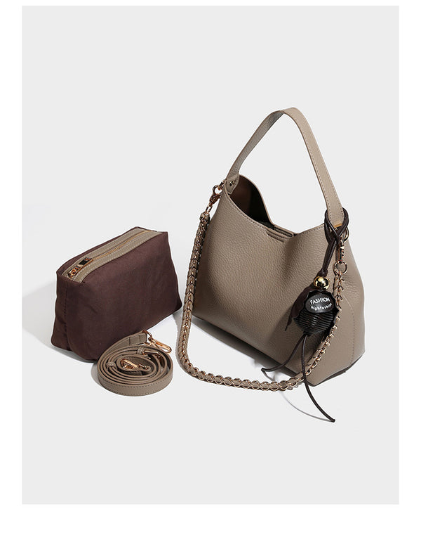 Hobo-Schultertasche in genarbtem Lederlook mit goldfarbener Kette als Schulterriemen, kurzem Tragegriff und dekorativem seitlichem Anhänger, Detailansicht