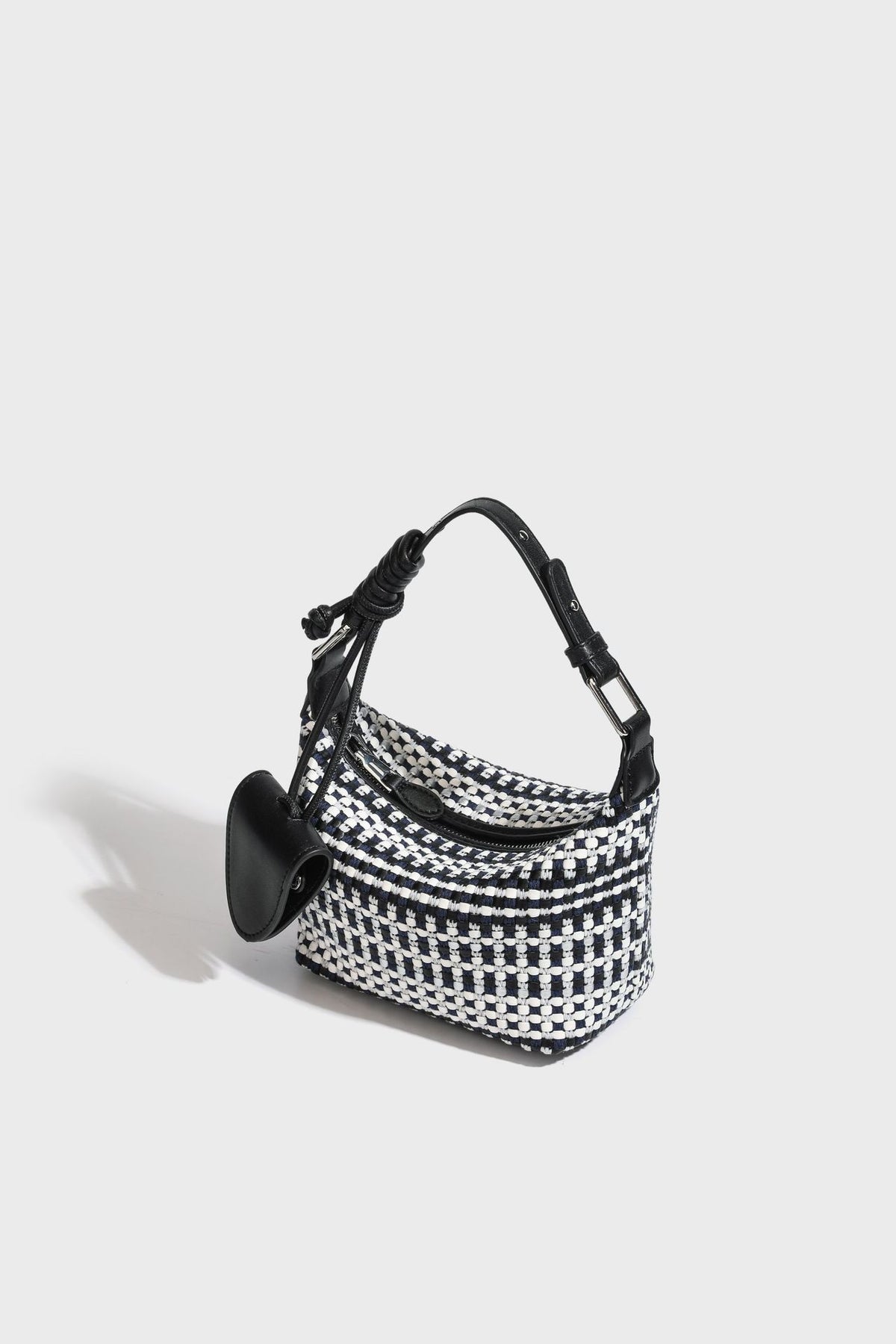 Small crescent shoulder bag in black-and-white woven textile with smooth black leather-look trim, zip-top closure, knotted