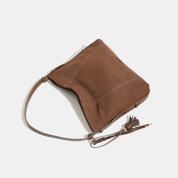 Slouchy suede-finish hobo shoulder bag in warm mocha brown with contrast stitching, braided tassel side accent, and, detail