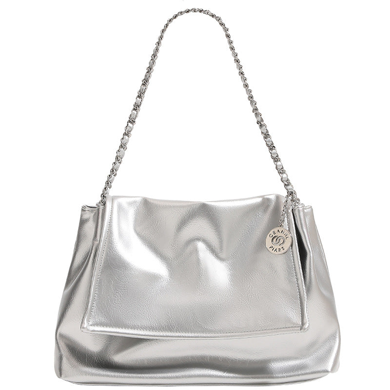 Soft trapezoidal chain-strap shoulder bag with foldover flap and circular logo medallion, detail view 5