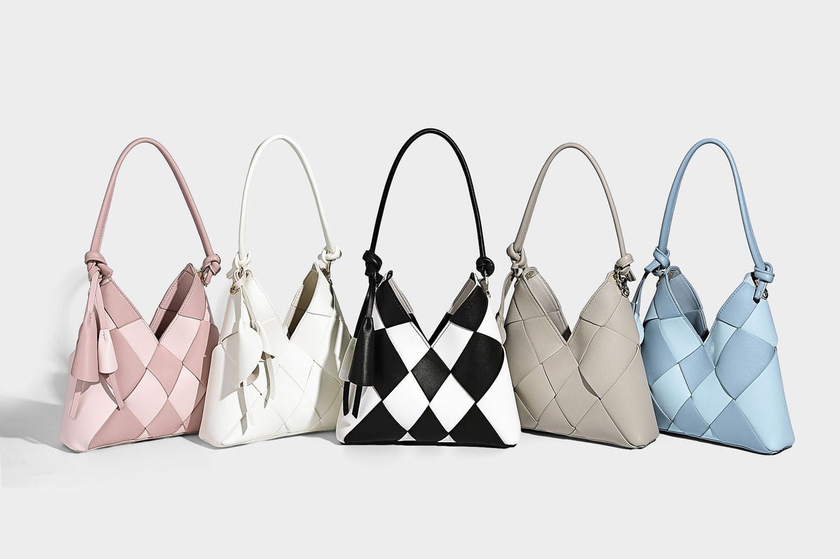 Compact bucket shoulder bag with black-and-white diamond patchwork panels, knotted top handle, gold-tone hardware, and