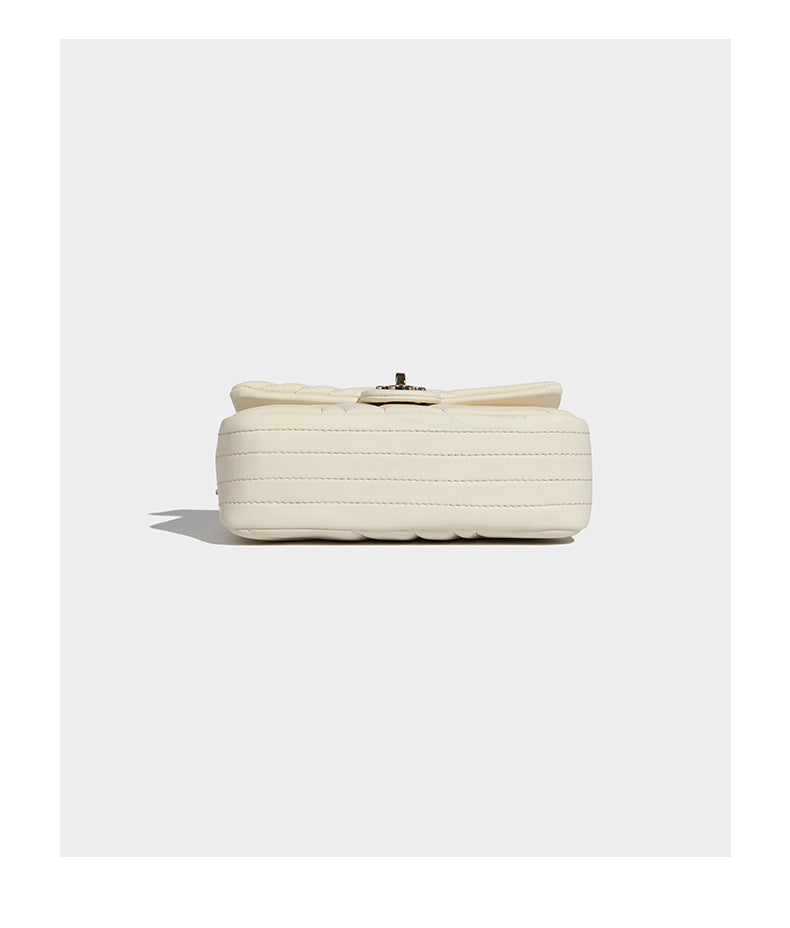 Compact cream quilted flap crossbody bag with wave stitching, gold-tone chain strap, and four-petal turn-lock clasp, detail