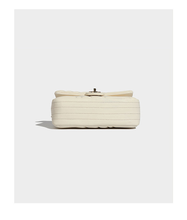 Compact cream quilted flap crossbody bag with wave stitching, gold-tone chain strap, and four-petal turn-lock clasp, detail