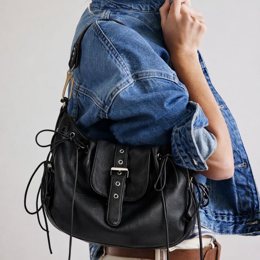 Black pebbled leather-look saddle shoulder bag with lace-up side panels, eyelet detail, and silver buckle flap, front view