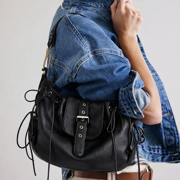 Schwarze Satteltasche aus genarbter Lederoptik mit geschnürten Seitenteilen, Ösendetails und Klappe mit silberfarbener Schnalle, Vorderansicht