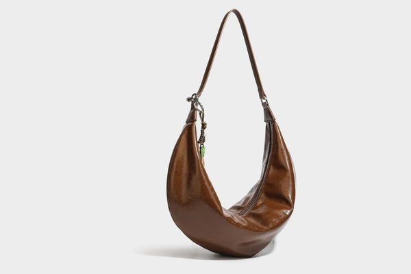 Lässig fallende Hobo-Schultertasche in Halbmondform mit glänzender, geknautschter Lederoptik, schmalem Riemen, silberfarbenen Ringbeschlägen und