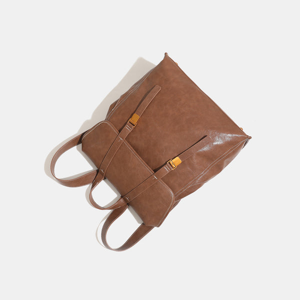 Structured leather-look flap backpack handbag with top handle, buckle front straps, white contrast stitching, and gold-tone