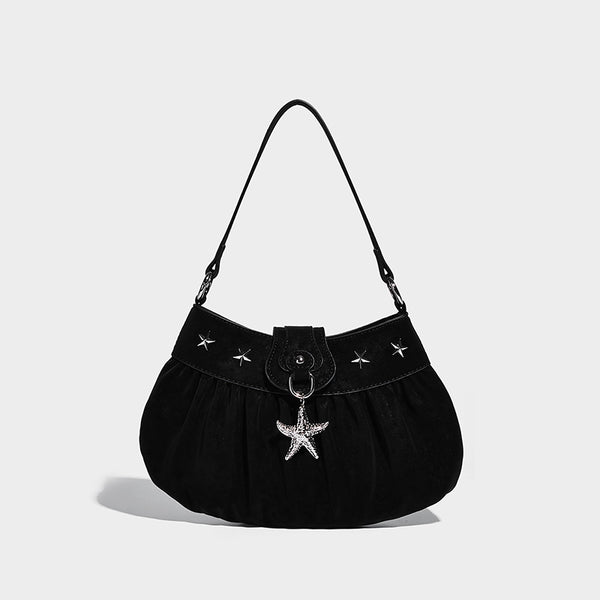Ruched shoulder bag with curved flap, silver star studs, dangling starfish charm, and adjustable crossbody strap, detail view