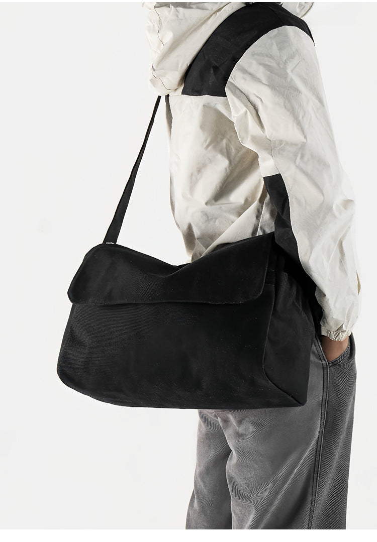 Große schwarze Messenger-Tasche aus mattem Canvas mit Überschlag vorn, Reißverschluss oben, elastischen Seitentaschen und verstellbarem silberfarbenem