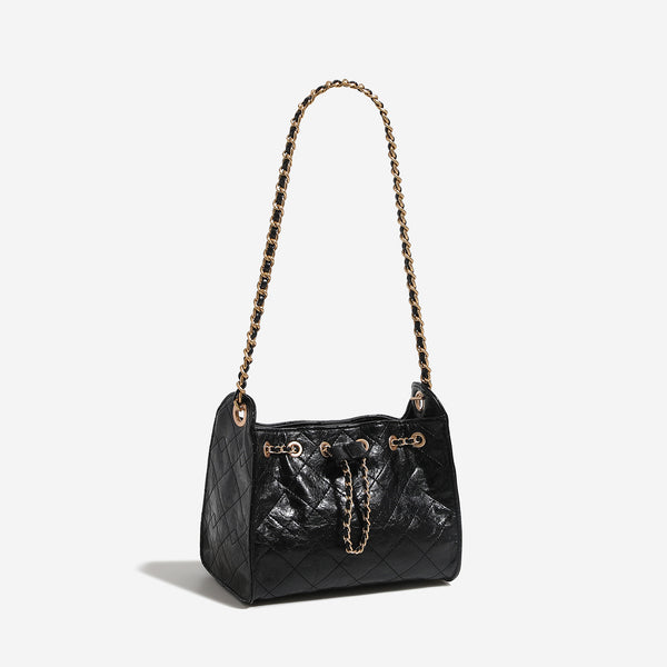Glossy diamond-quilted drawstring bucket bag with gold-tone chain strap and eyelet hardware, detail view 3