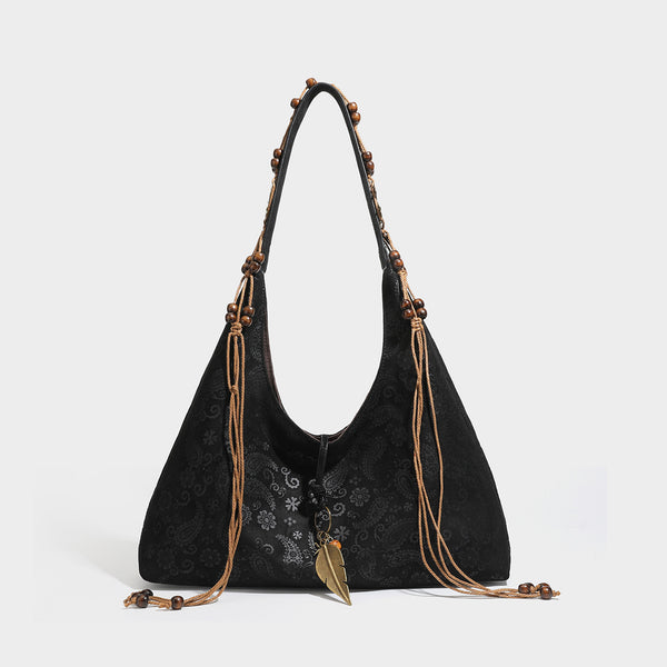 Slouchy boho hobo shoulder bag in embossed brown suede-look finish with beaded strap, cord tassels, and brass-tone leaf