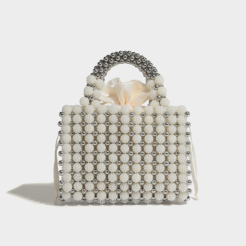 Small boxy pearl-bead mini top-handle bag with silver metallic bead accents, satin floral detail, and long beaded shoulder