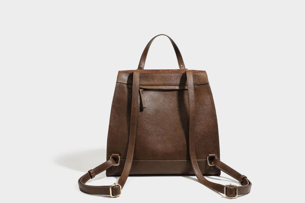 Structured suede-look convertible backpack handbag with flap closure and gold-tone emblem hardware in chocolate brown, detail