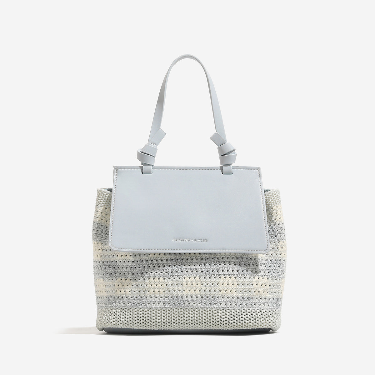 Small structured woven-body flap bag with smooth leather-look front panel, knotted top handle, and wide adjustable shoulder