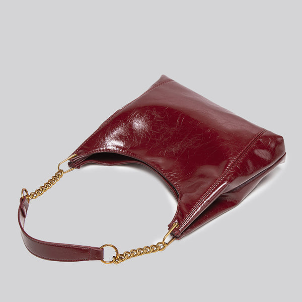 Glossy leather-look hobo shoulder bag with gold-tone chain-and-leather strap in deep burgundy red, detail view 4