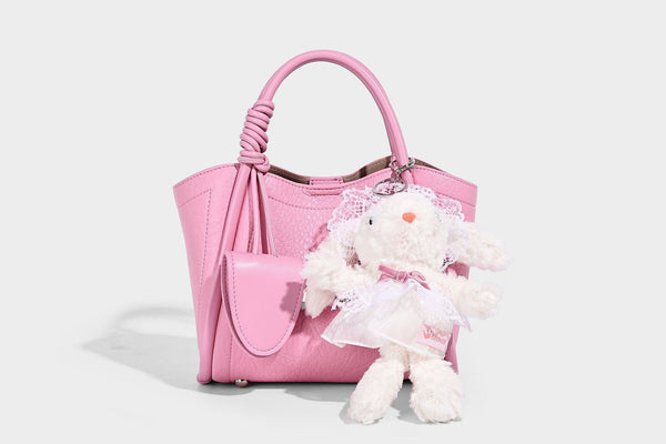 Structured mini tote bag in pebbled leather-look finish with knotted top handles, front flap pocket, and detachable shoulder