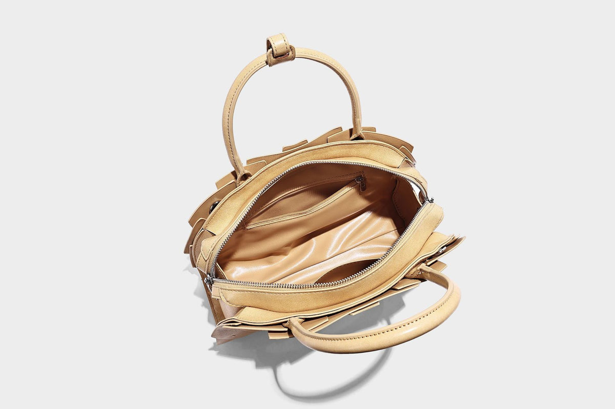 Structured dome satchel with fan-pleated leather-look exterior, dual top handles, and detachable shoulder strap, detail view