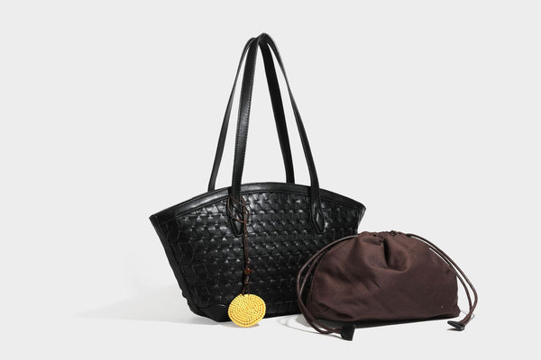 Large leather-look tote bag with geometric woven emboss, double shoulder straps, and round woven cord charm in brown, detail