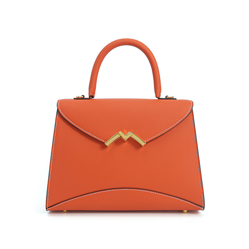 Structured trapezoid top-handle satchel in golden brown cross-grain textured finish with gold M-shaped clasp hardware and