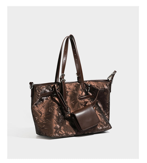 Glossy crinkled metallic-finish tote bag in brown with smooth leather-look top handles, silver-tone hardware, and attached