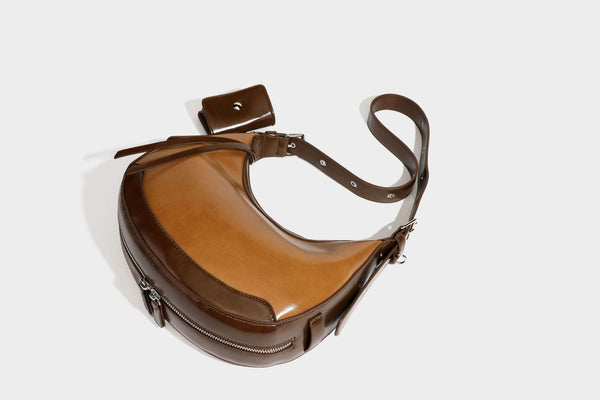 Glossy leather-look crescent hobo shoulder bag with dark contrast trim, silver-tone hardware, and attached mini flap pouch