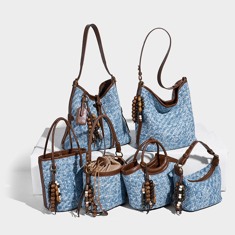 Small light blue woven bucket bag with brown leather-look trim, braided top handle, brass-tone ring hardware, drawstring