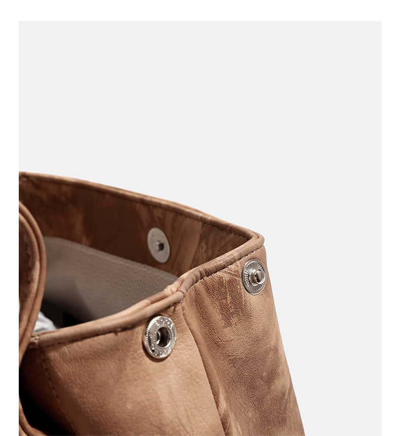 Compact distressed leather-look tan-brown backpack handbag with flap-and-buckle closure, two front patch pockets, top handle
