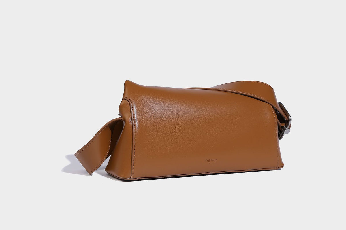Compact structured baguette shoulder bag with smooth leather-look finish, zip top, and adjustable silver-buckle strap, detail