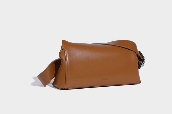 Compact structured baguette shoulder bag with smooth leather-look finish, zip top, and adjustable silver-buckle strap, detail