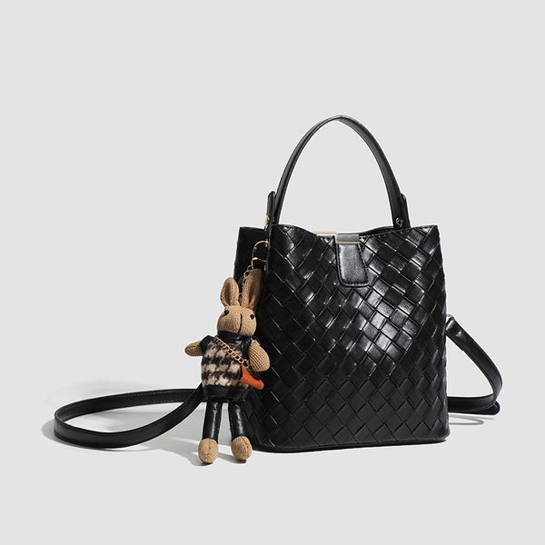 Black woven leather-look bucket bag with gold-tone clip closure, top handle, detachable shoulder strap, and knit bunny charm