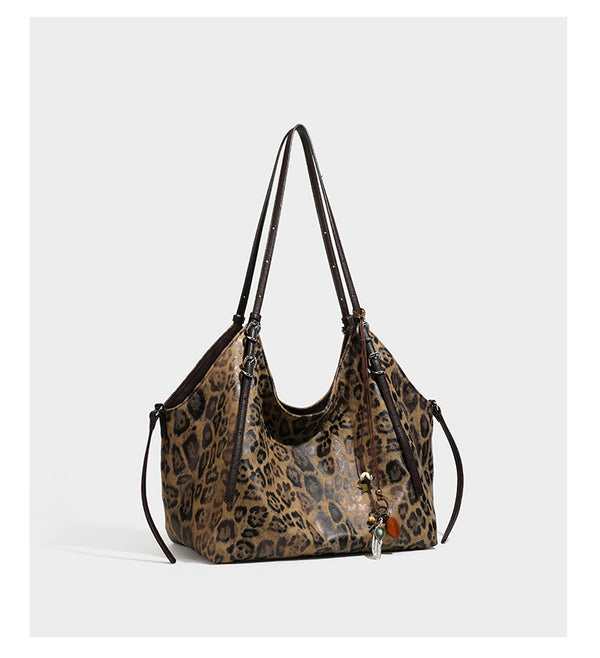 Slouchy leopard-print shoulder tote bag in tan and brown with long double straps, side tie straps, and dangling charm, detail