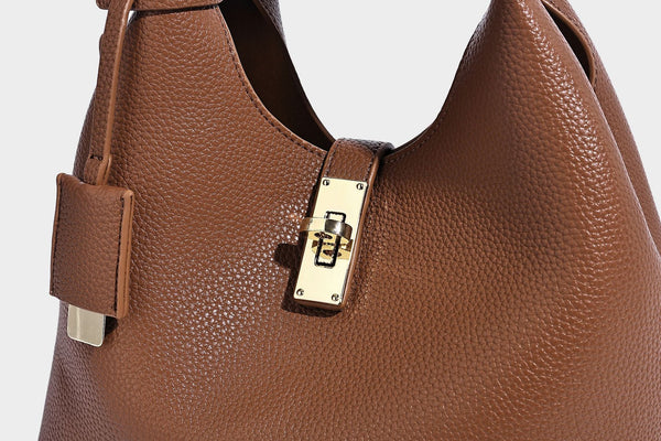 Structured pebbled-texture bucket bag with arched top handles, gold-tone turn-lock closure, and detachable shoulder strap