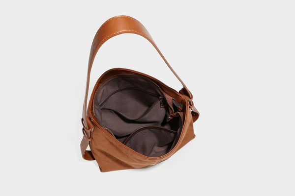 Slouchy suede-finish brown shoulder bag with long single strap and small gold-tone logo emblem on front, detail view 38